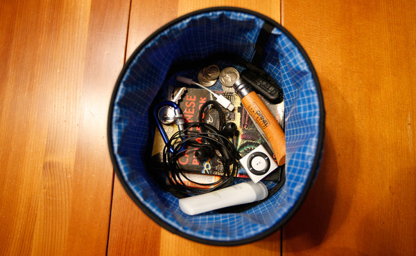 A Small Travel Tray holding a pair of headphone, a few tubes of lotion, and a pocket phrasebook.